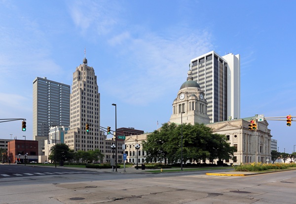 Downtown Fort Wayne, Indiana intersection featuring historic and modern buildings, traffic signals, and wide crosswalks, reflecting urban planning efforts focused on pedestrian safety and accessibility.