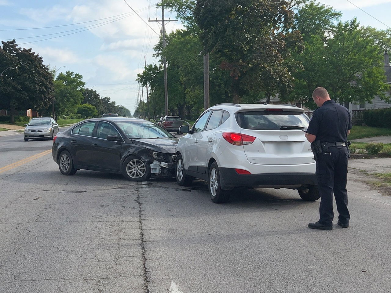 A police officer documenting a rear end collision between two vehicles on an Indiana street, illustrating a car accident case subject to the state's filing deadline for a lawsuit.